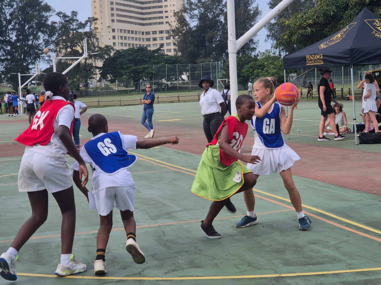 a netball match on the court. a player holding the ball about to pass