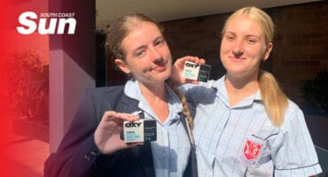 a pair of high school learners holding a card