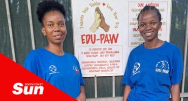 two woman standing in front of a sign