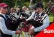 a band of bagpipe players dressed in Highland Games garb, kilts, argyll jackets, sorrans and all.