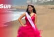a teenager wearing a pink princess dress, a pageant sash and a tiara on the beach