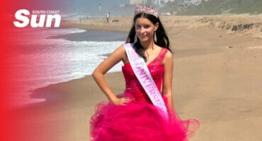 a teenager wearing a pink princess dress, a pageant sash and a tiara on the beach