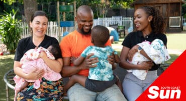 three adults holding three little children and smiling