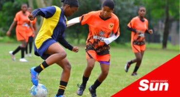 soccer players on the field. a defender holds off tackling players