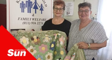 two woman holding a quilt