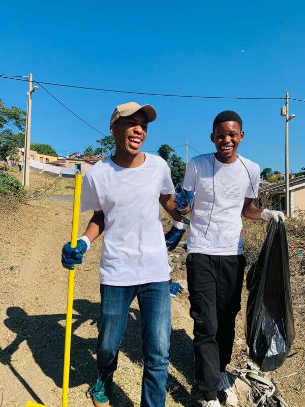 two boys with a rake, rubbish bag and rubber gloves