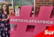 a woman poses next to a giant hashtag statue