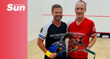 a duo of squash players in the court holding their racquets