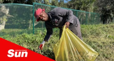 a man holding a rubbish bag, picking up litter