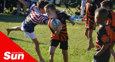 a young minis rugby player weaving past a defender during his run