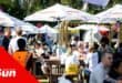 Crowds sitting under umbrellas eating and drinking