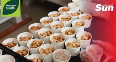 Meals packed into take away containers lined in rows on a counter top