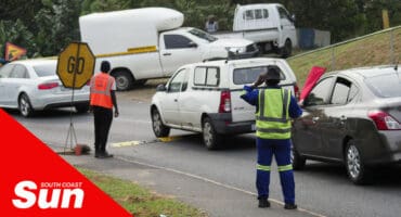 traffic slowly moving, being guided by traffic officers. cars driving over a low-profile metal speed bump