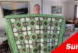 a man holding a large handmade quilt