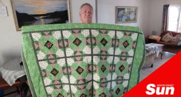 a man holding a large handmade quilt