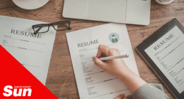 a person writing a curriculum vitae on a table.