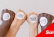 multiple hands and forearms of different complexions with voting stickers on the top