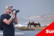a photograph of horses on the beach, inset of a photographer