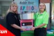 a woman receiving a candy floss machine donation from another woman