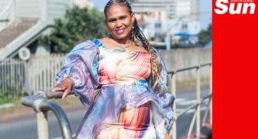a woman's portrait, she is smiling and showing off her self-designed and handmade outfit