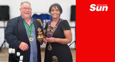 two people smiling together, one handing the other a trophy