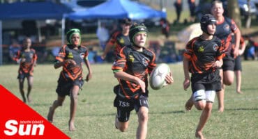 young rugby players on the field. player with possession of the ball is running ahead of the pack