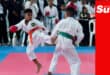 Two young martial arts fighters spar on a tatami with crowds of spectators watching