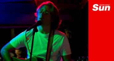 a musician plays guitar and sings on stage