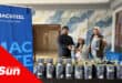 a group photograph at a school with people holding buckets of metal paint