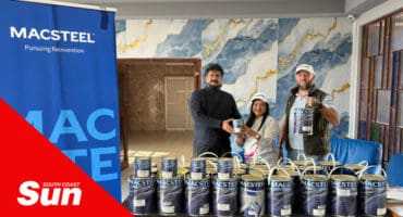 a group photograph at a school with people holding buckets of metal paint