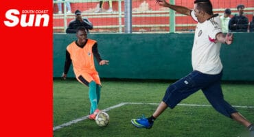 a soccer player with possession of the ball taunts a defender