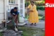 a woman shoveling sewage outfall away from a property's backyard while a woman using crutches watches
