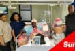 people handing over a get well soon hamper to a hospital patient who has a head bandage on.