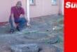 a man pointing at manholes outside a flat building