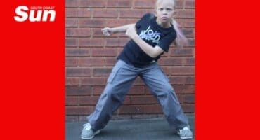 a child dancing in front of a brick wall