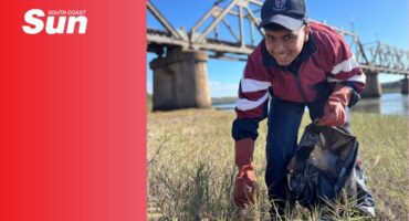 a high school learner cleans up a beach with a rubbish bag