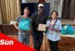 a group photograph with people happy and smiling, holding a grocery donation from a charity organisation