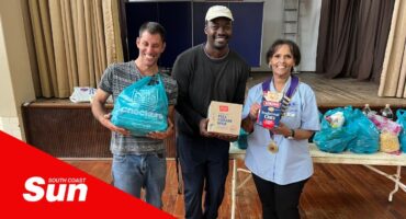 a group photograph with people happy and smiling, holding a grocery donation from a charity organisation