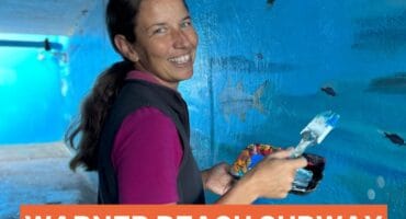 a woman in a subway painting a mural