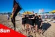 on the beach, a group photograph of young lifesaving nippers waving a banner