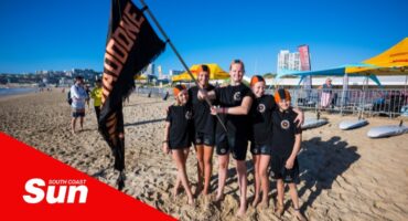 on the beach, a group photograph of young lifesaving nippers waving a banner