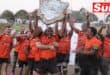 a team of rugby players lift a shield trophy in celebration