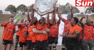 a team of rugby players lift a shield trophy in celebration