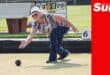 a woman on a field bowling, delivering a ball