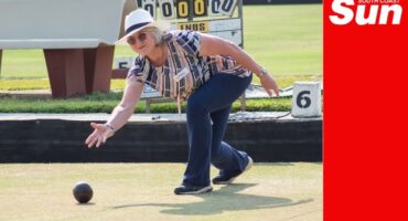 a woman on a field bowling, delivering a ball