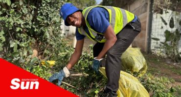 a man cleaning overgrown vegetation along the community staircase