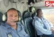 two men take a photograph in a helicopter