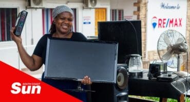 a woman holds a monitor and a remote during an electronic waste recycling drive