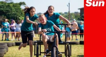 a school child races on a soap box cart around a makeshift track with tires