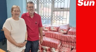 a man and a woman in front of tons of porridge that they donated